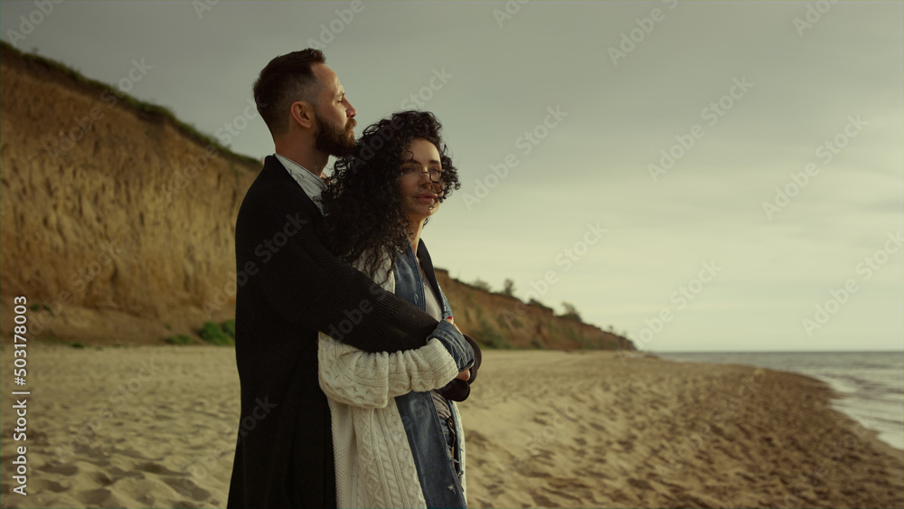 Couple cuddling beach sea on holiday. Happy mixed race lovers hug at ocean shore
