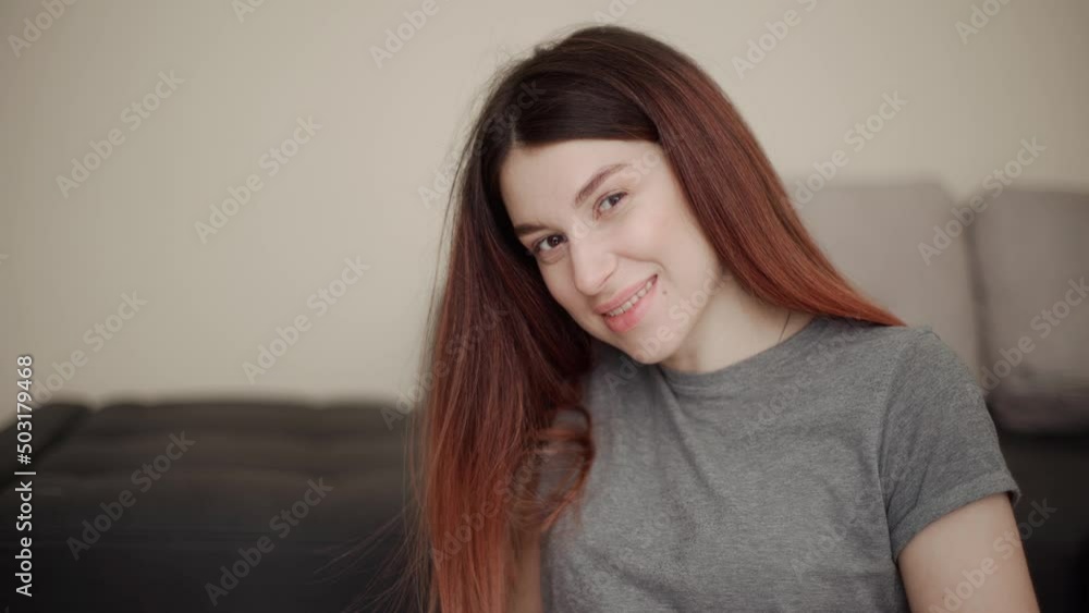 Young pregnant dark-haired woman in a gray T-shirt with a smile looks at the camera and gently strokes her belly Young pregnant dark-haired woman in a gray T-shirt with a smile looks at the camera and gently strokes her belly