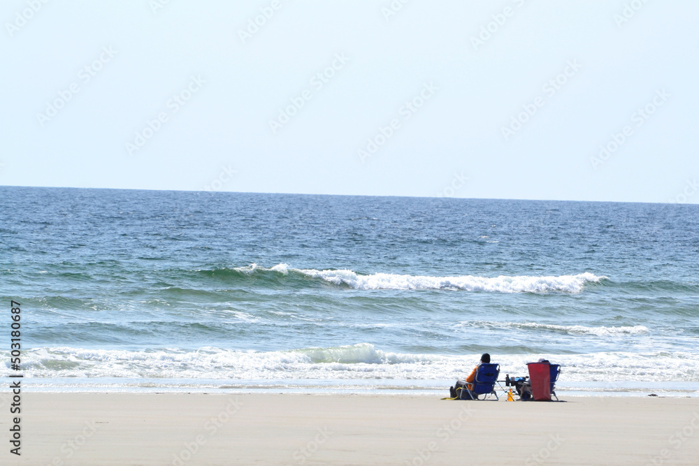 A Couple Sitting on the Beach Watching the Waves in Spring A Couple Sitting on the Beach Watching the Waves in Spring