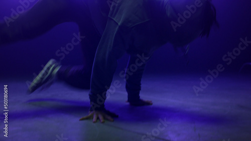 Dancer man performing breakdance in nightclub close up. Agile guy spinning body 