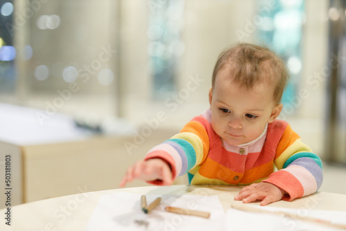 Education the child by playing. Kid drawing on paper with crayons. Portrait of sweet toddler girl.