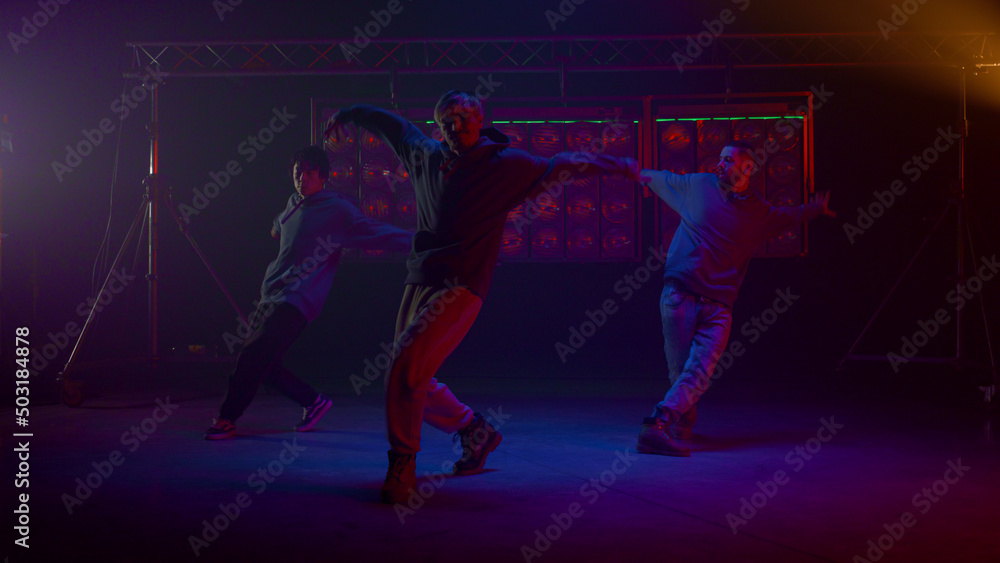 Cool guys dancing hiphop in flashing backlights. Dancers performing on stage.