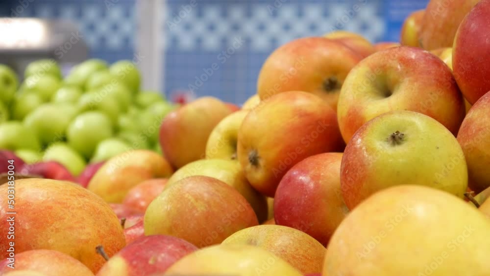 Close-up of a bunch of fresh ripe apples in the market and a male hand takes one Close-up of a bunch of fresh ripe apples in the market and a male hand takes one