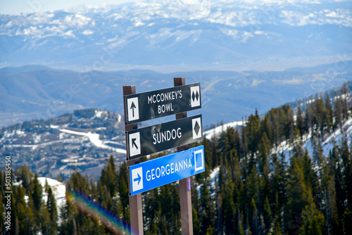 Trail sign at Park City Ski Area, Utah. Top view to the valley with mountains range during early spring weather conditions.