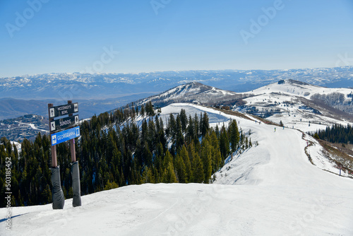 Trail sign at Park City Ski Area, Utah. Top view to the valley with mountains range during early spring weather conditions.