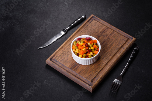A mixture of chopped vegetables paprika, corn, peas in white plate