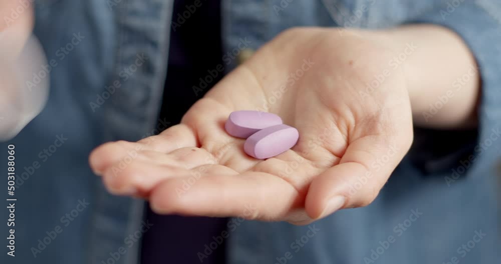 Two medical pills are poured from the container into the hand. Vitamins close-up. Two medical pills are poured from the container into the hand. Vitamins close-up.