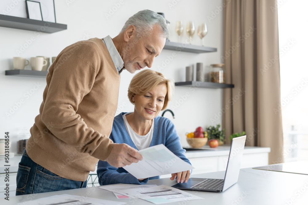 Middle aged couple checking finance account together Middle aged couple checking finance account together