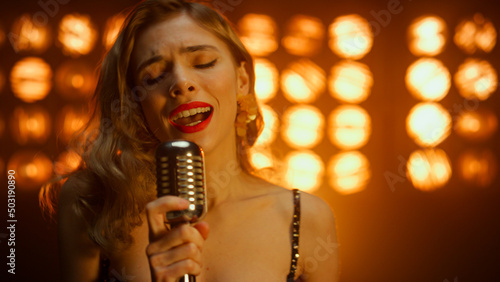 Obraz na plátne Attractive girl vocalist singing holding microphone on stage night club close up