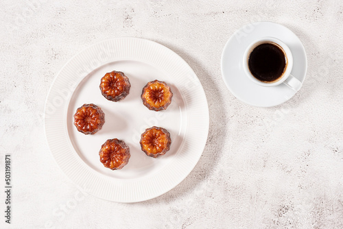 A cup of coffee and French dessert canele on grey background