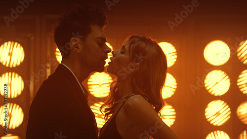 Sensual couple dancing intimately at club lights. Young man caressing hot girl.