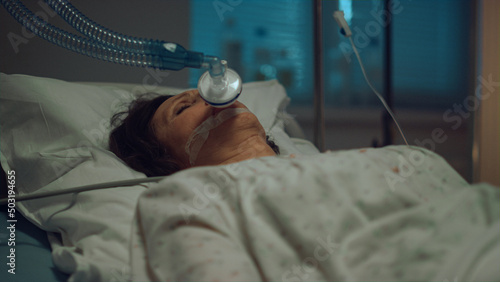 Patient with oxygen mask lying hospital bed in hospital intensive care unit. 