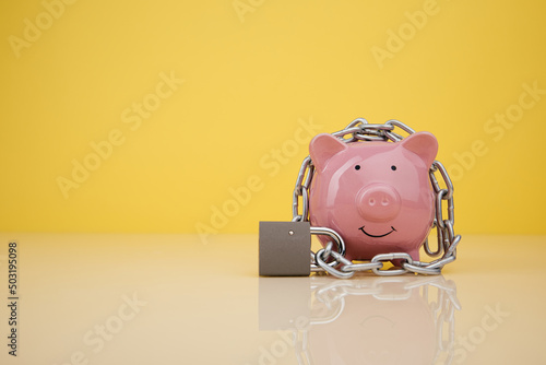 Piggy bank with chain on yellow background. Money security concept