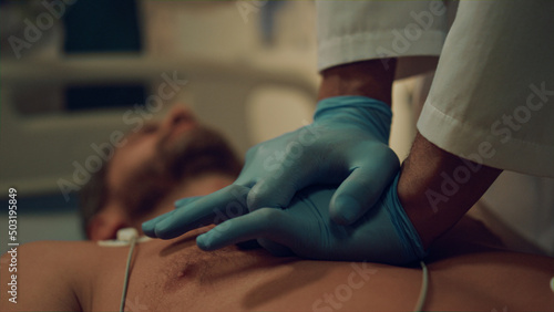 Closeup doctor doing heart massage to unconscious patient in hospital ward.