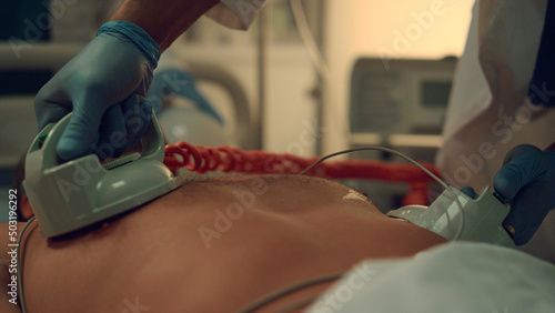 Doctor hands defibrillating patient in hospital emergency facility close up. 
