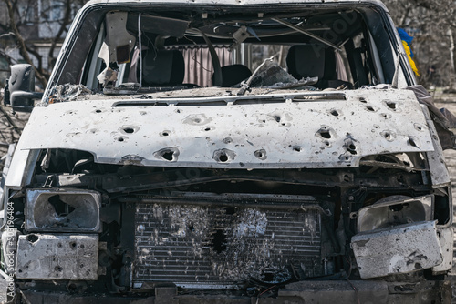 The minibus was shot to pieces. Blue and yellow flag looks out the side window (concept of Russian military aggression)