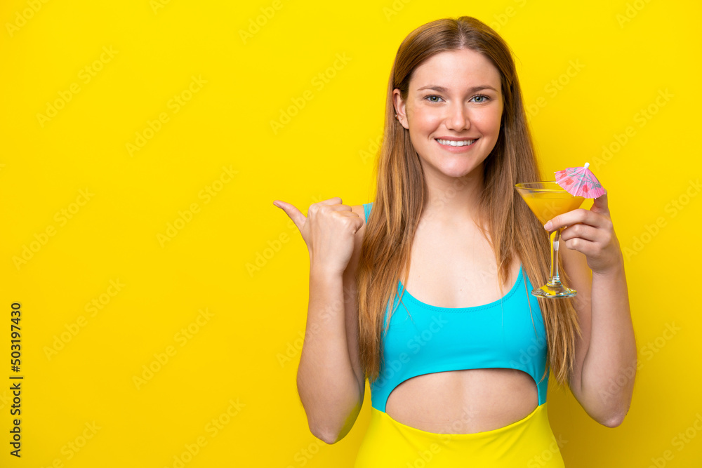 Young caucasian woman holding a cocktail isolated on yellow background pointing to the side to present a product Young caucasian woman holding a cocktail isolated on yellow background pointing to the side to present a product