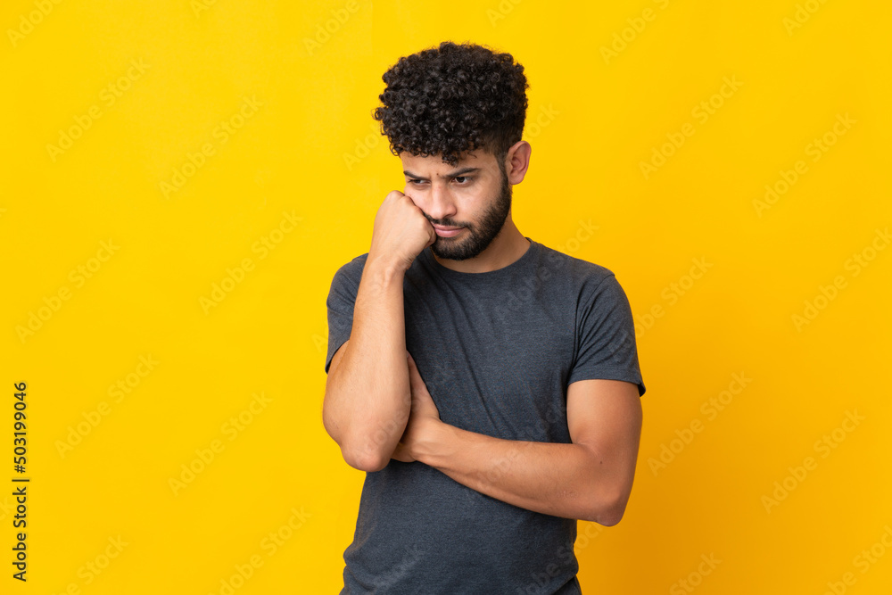 Young Moroccan man isolated on yellow background with tired and bored expression Young Moroccan man isolated on yellow background with tired and bored expression