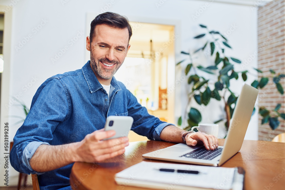 © baranq - Successful man using smart phone and laptop at home office © baranq - Successful man using smart phone and laptop at home office