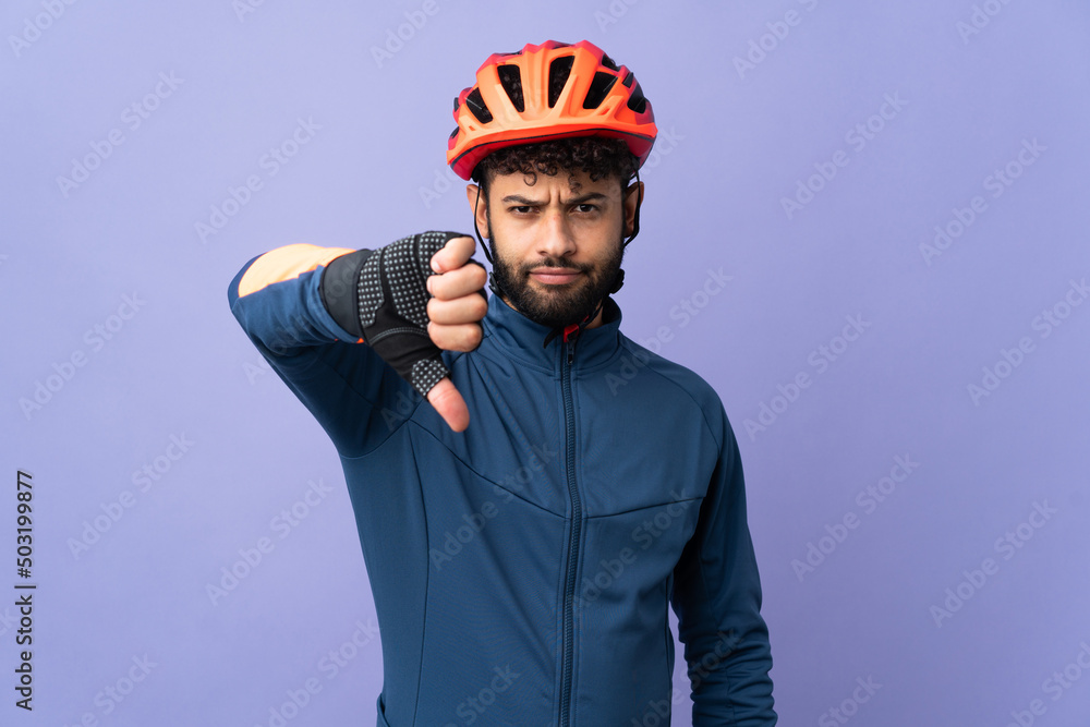 Young Moroccan cyclist man isolated on purple background showing thumb down with negative expression Young Moroccan cyclist man isolated on purple background showing thumb down with negative expression
