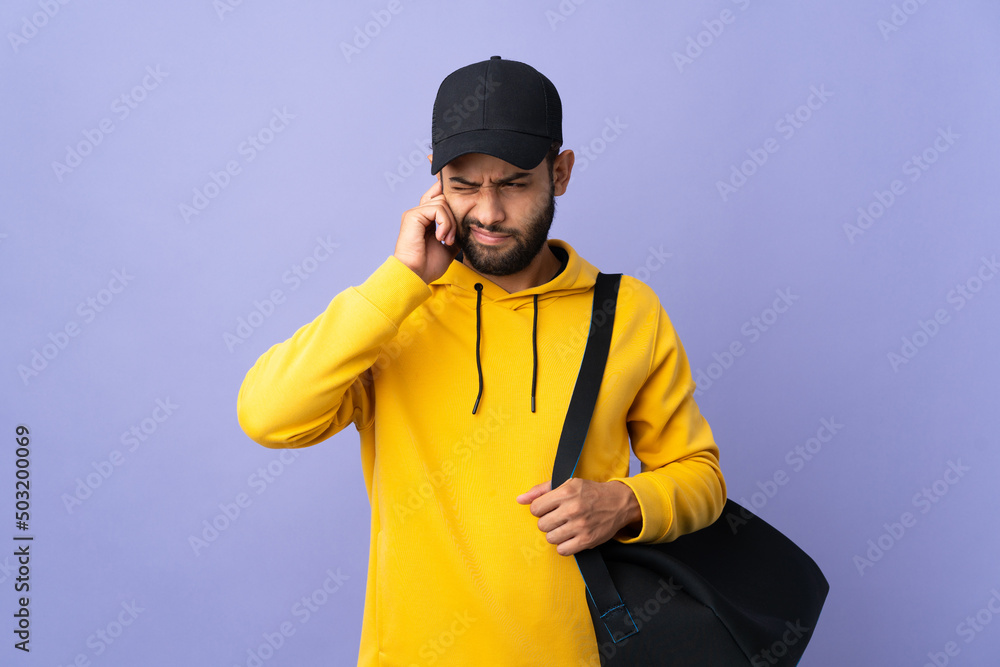 Young sport Moroccan man with sport bag isolated on purple background frustrated and covering ears Young sport Moroccan man with sport bag isolated on purple background frustrated and covering ears