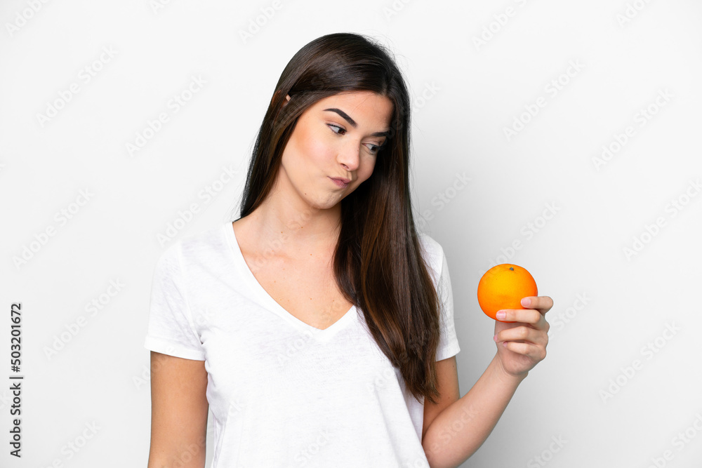 Young Brazilian woman holding an orange isolated on white background with sad expression Young Brazilian woman holding an orange isolated on white background with sad expression