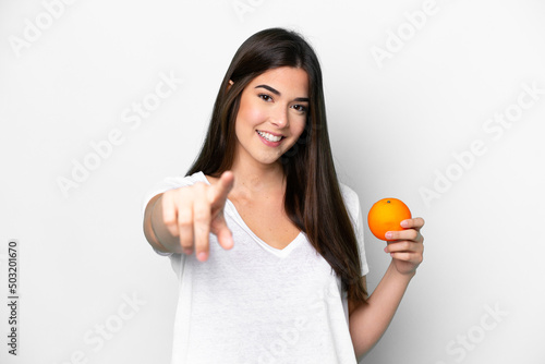 Young Brazilian woman holding an orange isolated on white background points finger at you with a confident expression