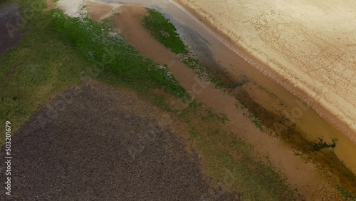 Aerial drone view flying over green cliffs onto a huge sandy beach at low tide Three Cliffs Bay, Gower, Wales photo