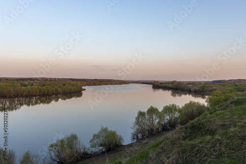 Fototapeta Naklejka Na Ścianę i Meble -  Evening landscape. Cloudy May day. Clouds are reflected in the lake. Peaceful landscape on the banks of the reservoir. Relax in nature.