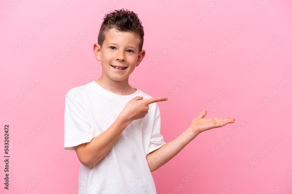 Little caucasian boy isolated on pink background holding copyspace imaginary on the palm to insert an ad Little caucasian boy isolated on pink background holding copyspace imaginary on the palm to insert an ad