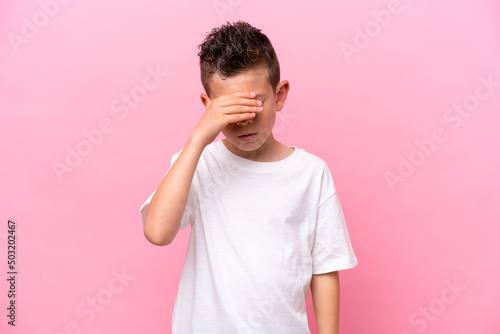 Little caucasian boy isolated on pink background with headache