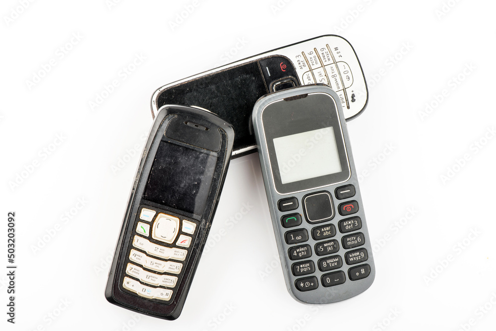 Old mobile phone in different colors. Retro technology of cellular devices located on a white background. Old technical display Old mobile phone in different colors. Retro technology of cellular devices located on a white background. Old technical display