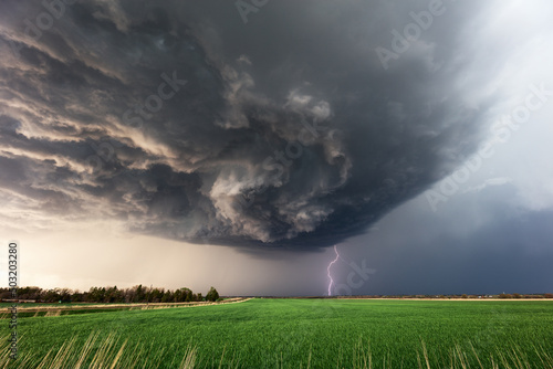 Tela Dramatic supercell storm clouds and lightning strike over a field