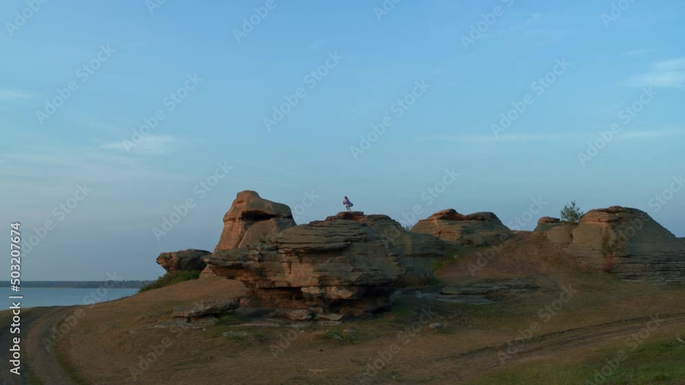 A girl is doing fitness on a hill on the lake shore A girl is doing fitness on a hill on the lake shore