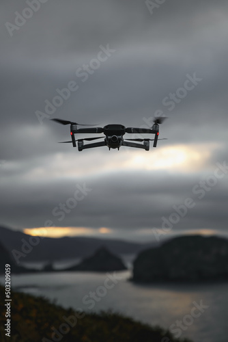 Foldable drone copter flying with a digital camera in mountains.