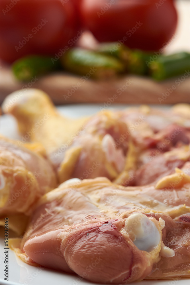 Chicken pieces placed on a plate, garnish tomatoes and chili peppers placed on a wood. Chicken pieces placed on a plate, garnish tomatoes and chili peppers placed on a wood.