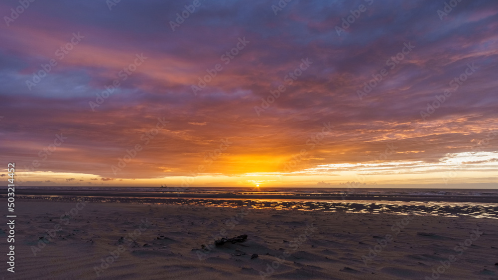 Beautiful sunset with dramatic moody cloudy sky above the ocean of North Sea, De Haan, Belgium.