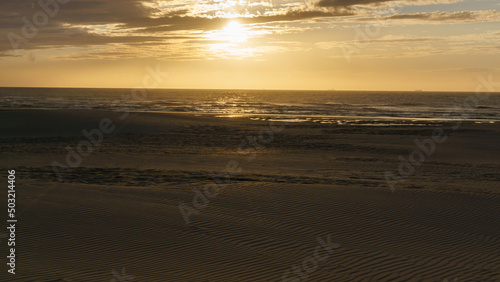 sunset during golden hour at sandy beach, De Haan, Belgium