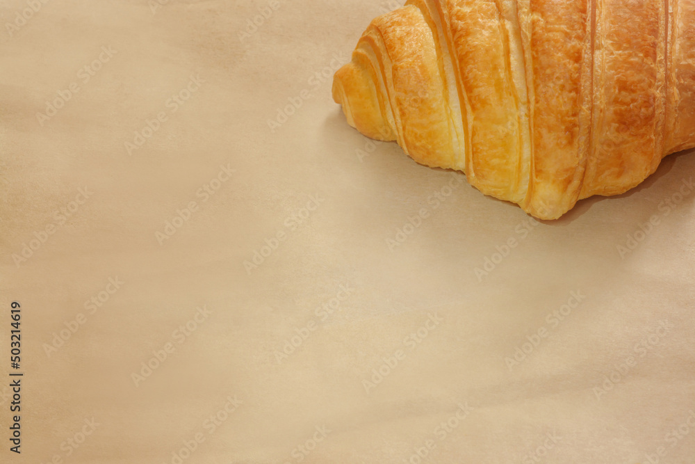 Beige kraft paper background with a croissant in the upper right corner, with copy space Beige kraft paper background with a croissant in the upper right corner, with copy space