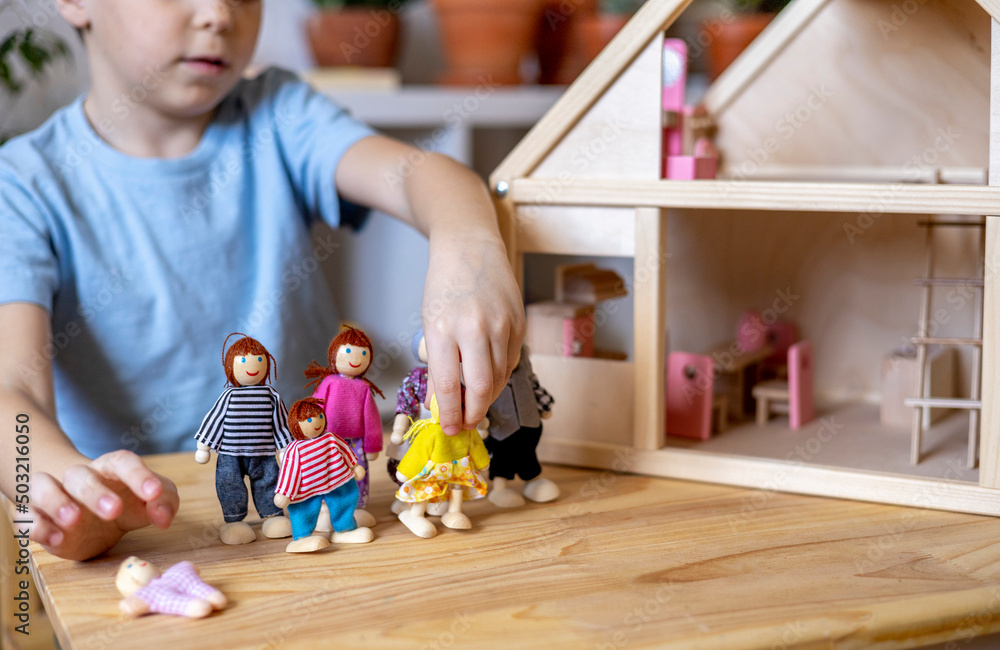 Fototapeta premium Montessori material. Toddler while playing with big pink dollhouse and having a great time.