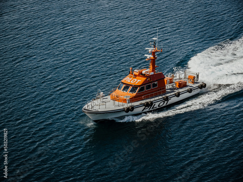 A Harbor Pilot Boat meets a ship to retrieve the Harbor Pilot who has supervised the departure navigation of the ship out of the harbor.