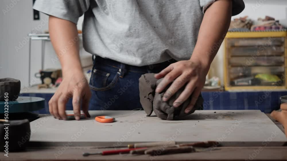 Anonymous man using wire cut with clay in pottery studio. Young people cutting clay with rope. Concept of education, business, art talent and creative handmade. Anonymous man using wire cut with clay in pottery studio. Young people cutting clay with rope. Concept of education, business, art talent and creative handmade.