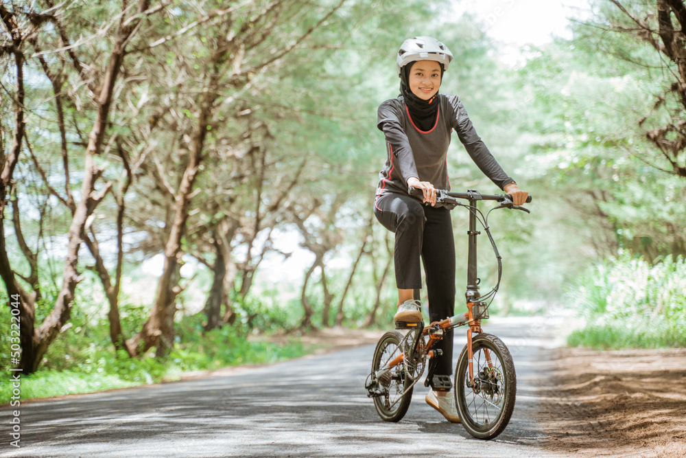 Asian woman in sportswear and helmet while cycling on outdoor background