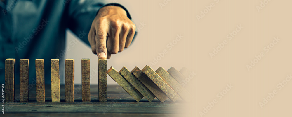 Hand prevent wooden block tower stack crash or fall domino. concept of prevention of financial business and risk management or strategic planning. - obrazy, fototapety, plakaty 