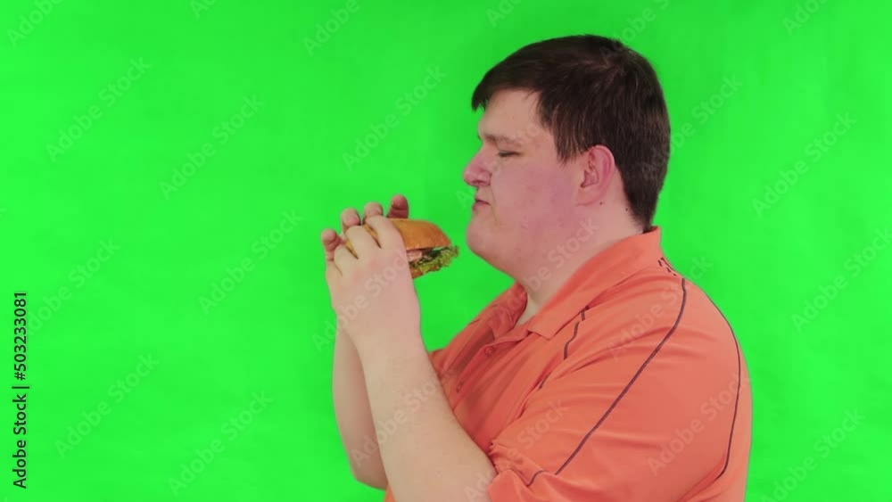 Portrait of a fat guy eating a big burger isolated on a green ...