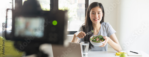 Social media and content creator occupation new job in future. beauty asian blogger eating fresh homemade salad breakfast and recording video for online channel live.