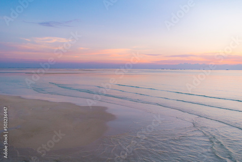 グラデーションの綺麗な夕焼けと海と浜 沈む太陽 癒しリラックスイメージ 地平線の背景素材