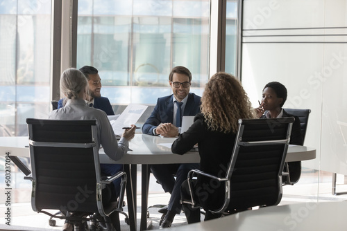 Diverse millennial business group brainstorming, at conference table. Startup leaders, project investors meeting, analyzing marketing reports, negotiating on investment, deal