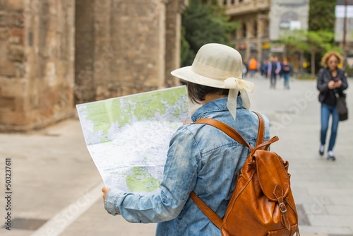 Latin tourist consulting the map in the gothic quarter of Barcelona (Spain), travel concept, selective approach to the cap.