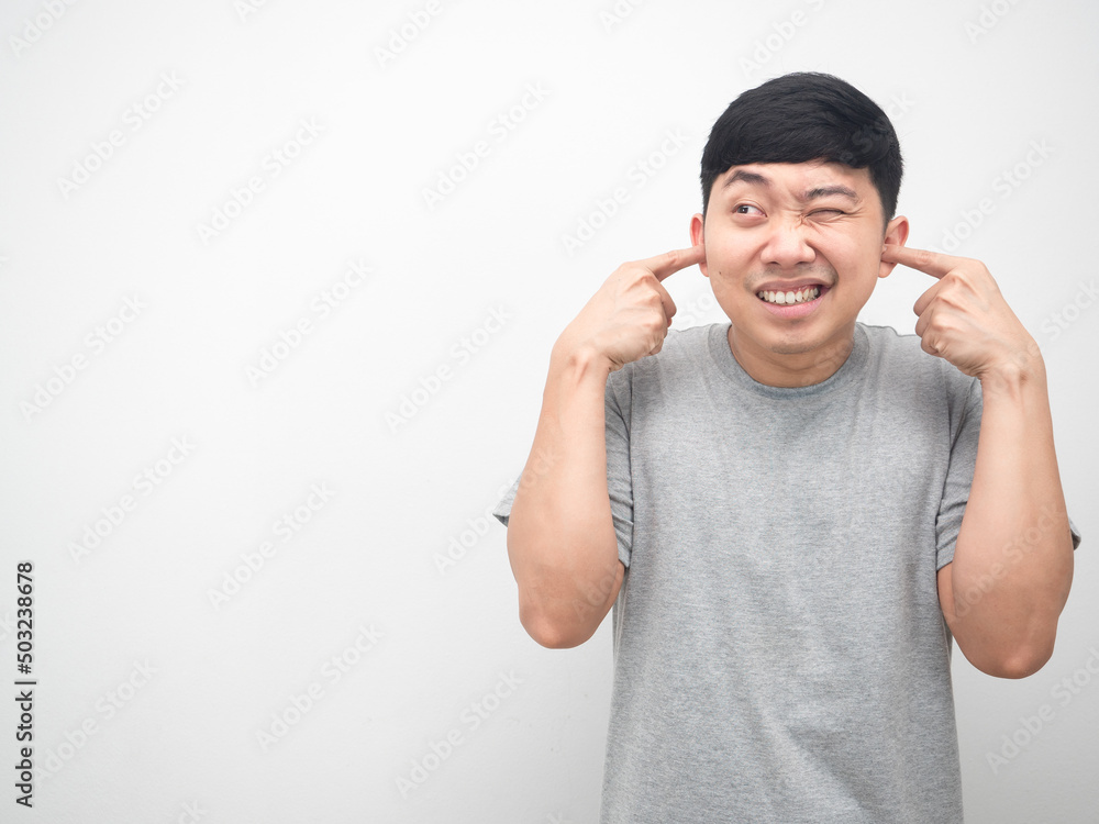 Fototapeta premium Man gesture plug finger close his ear and looking at copy space white background